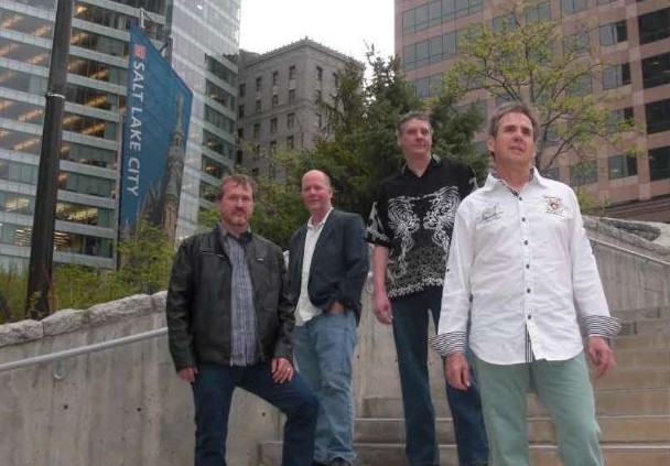 Four men from the BD Howes Band standing in front of some buildings. 